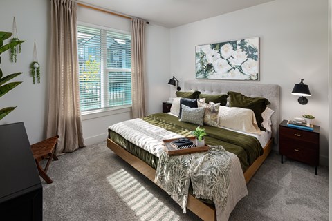 A bedroom with a large bed and a window with curtains.