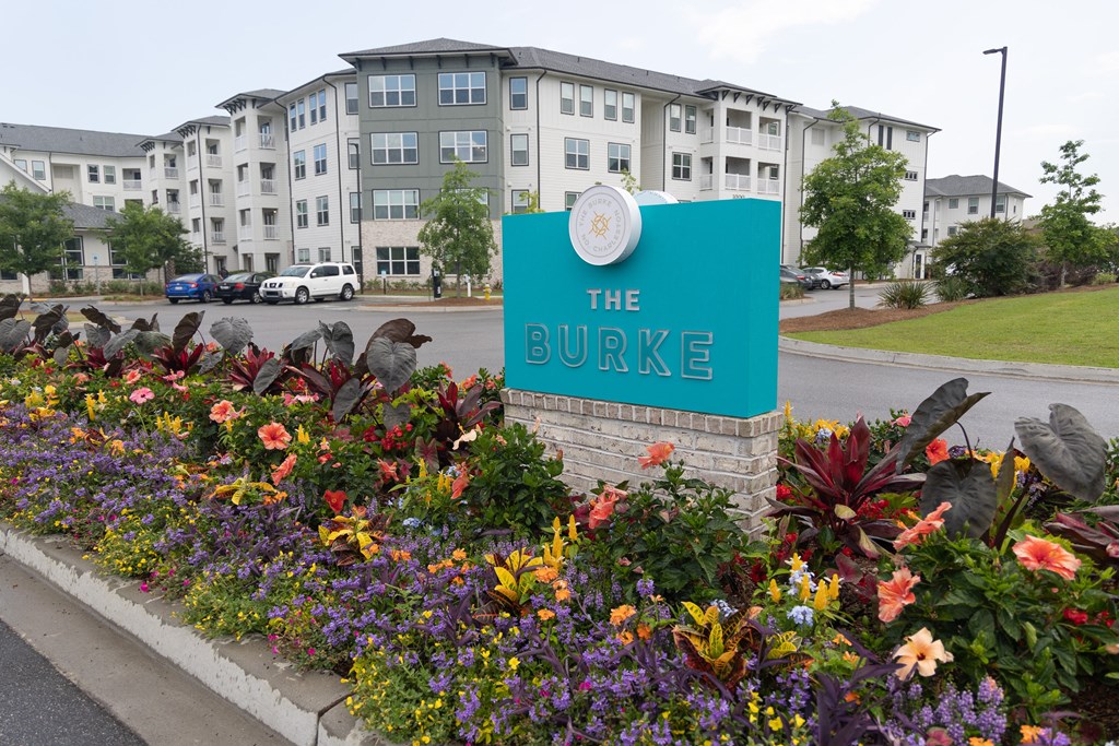 the apartments entrance sign in front of a flower garden