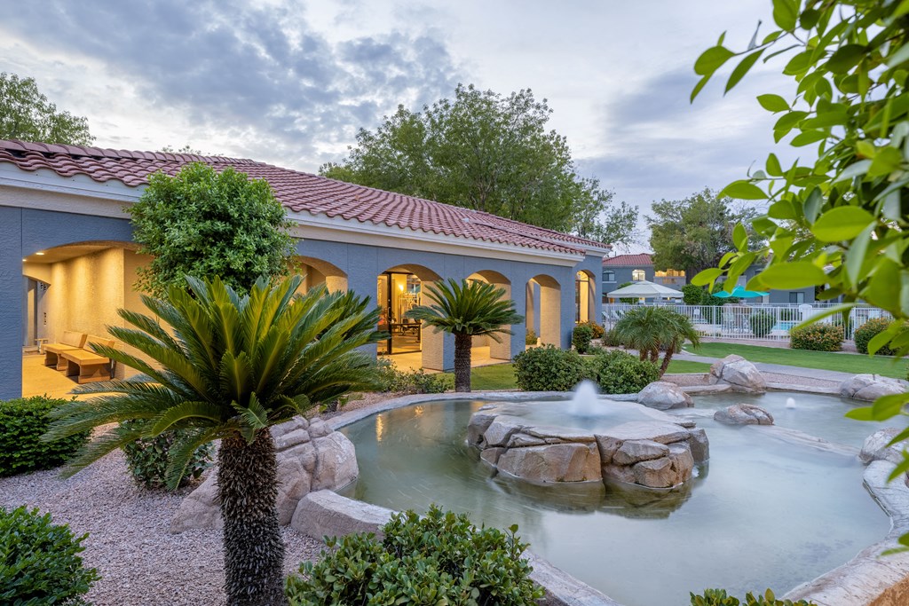 a swimming pool with a fountain in front of a house