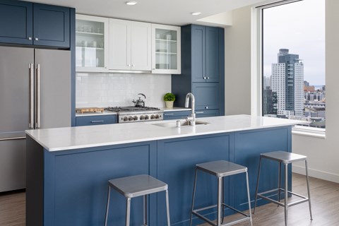 a kitchen with blue cabinets and white counter tops and three stools