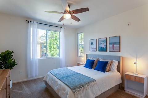 A bedroom with a large bed and a ceiling fan.