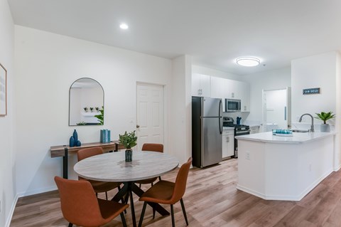 A kitchen with a table and chairs in the foreground and a refrigerator in the background.