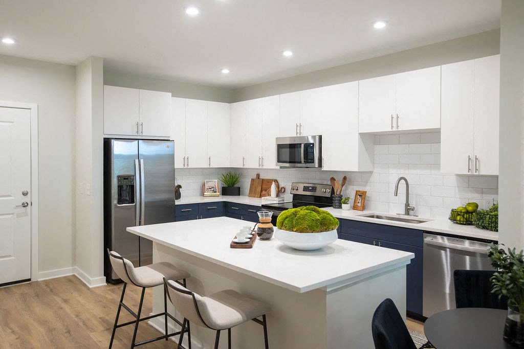 a kitchen with a white counter top and a stainless steel refrigerator