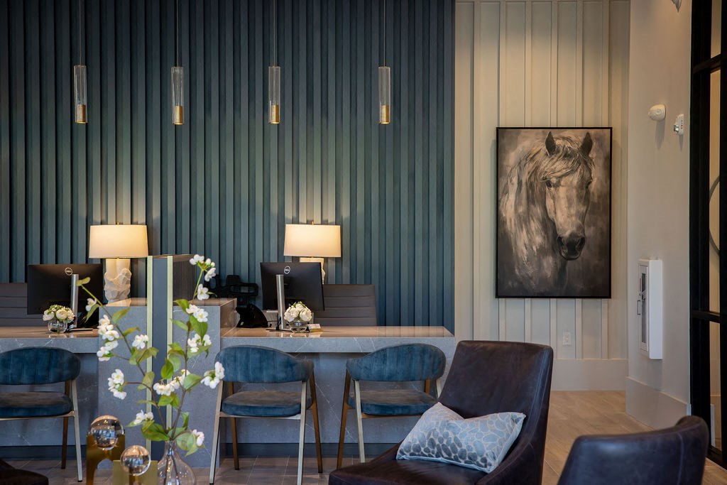 a living room with blue chairs and a table with a horse painting