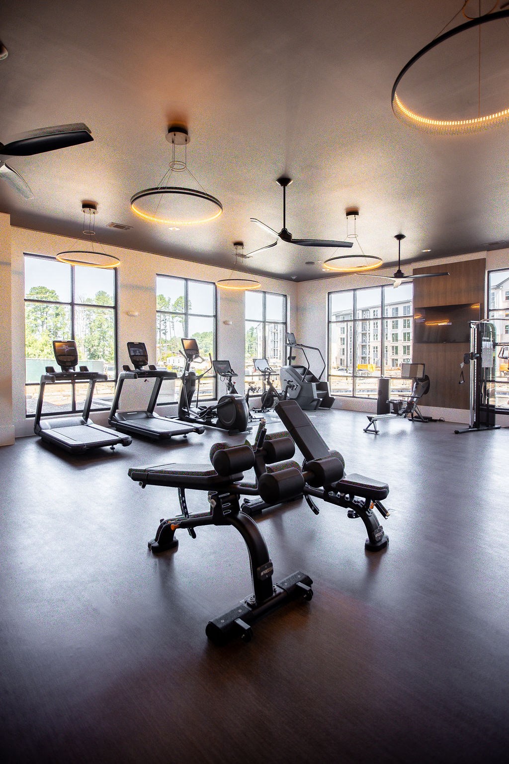 a workout room with weights and chairs in a large room with windows