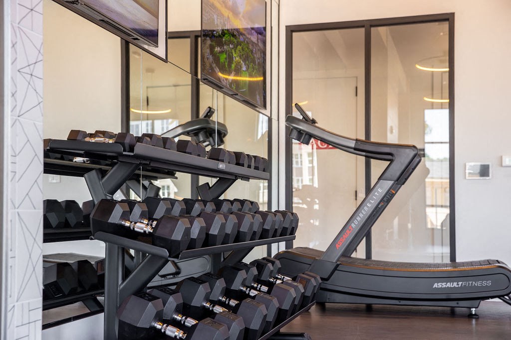 a treadmill and weights in a gym with glass doors