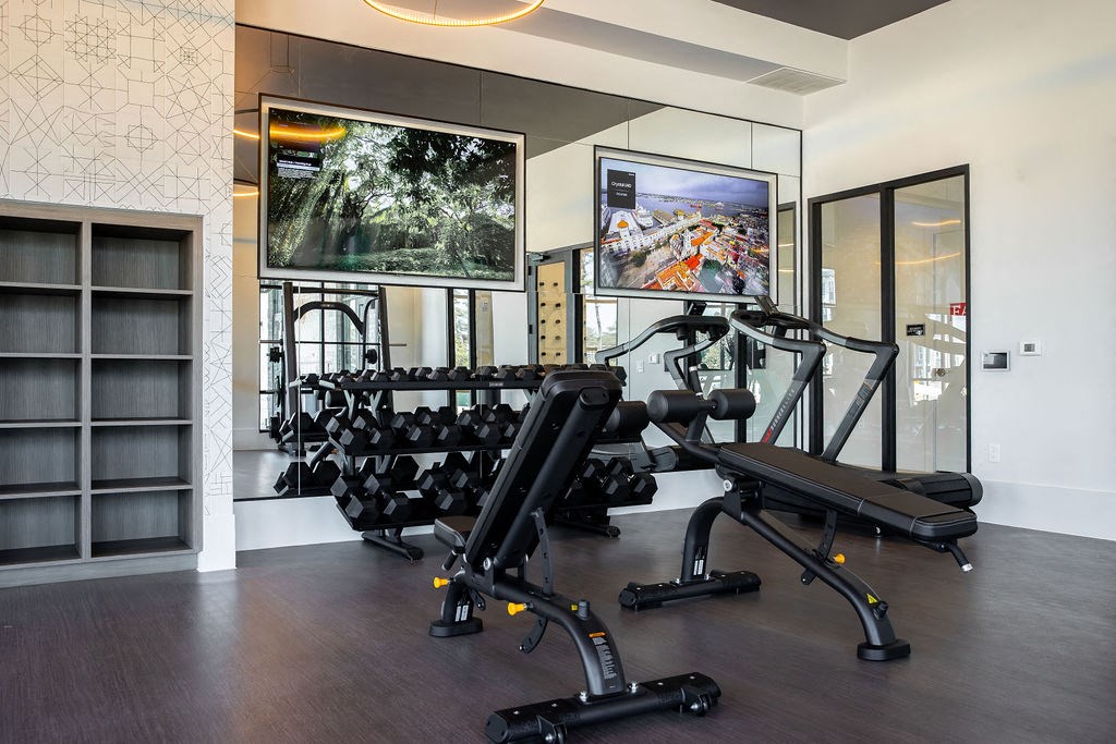 a gym with weights and a tv on the wall