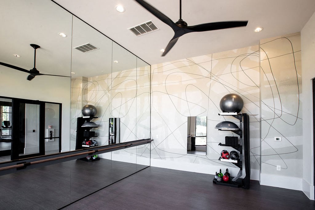 a home gym with mirrored walls and a ceiling fan