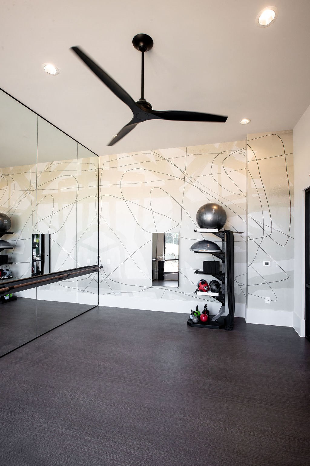 a living room with a ceiling fan and glass walls
