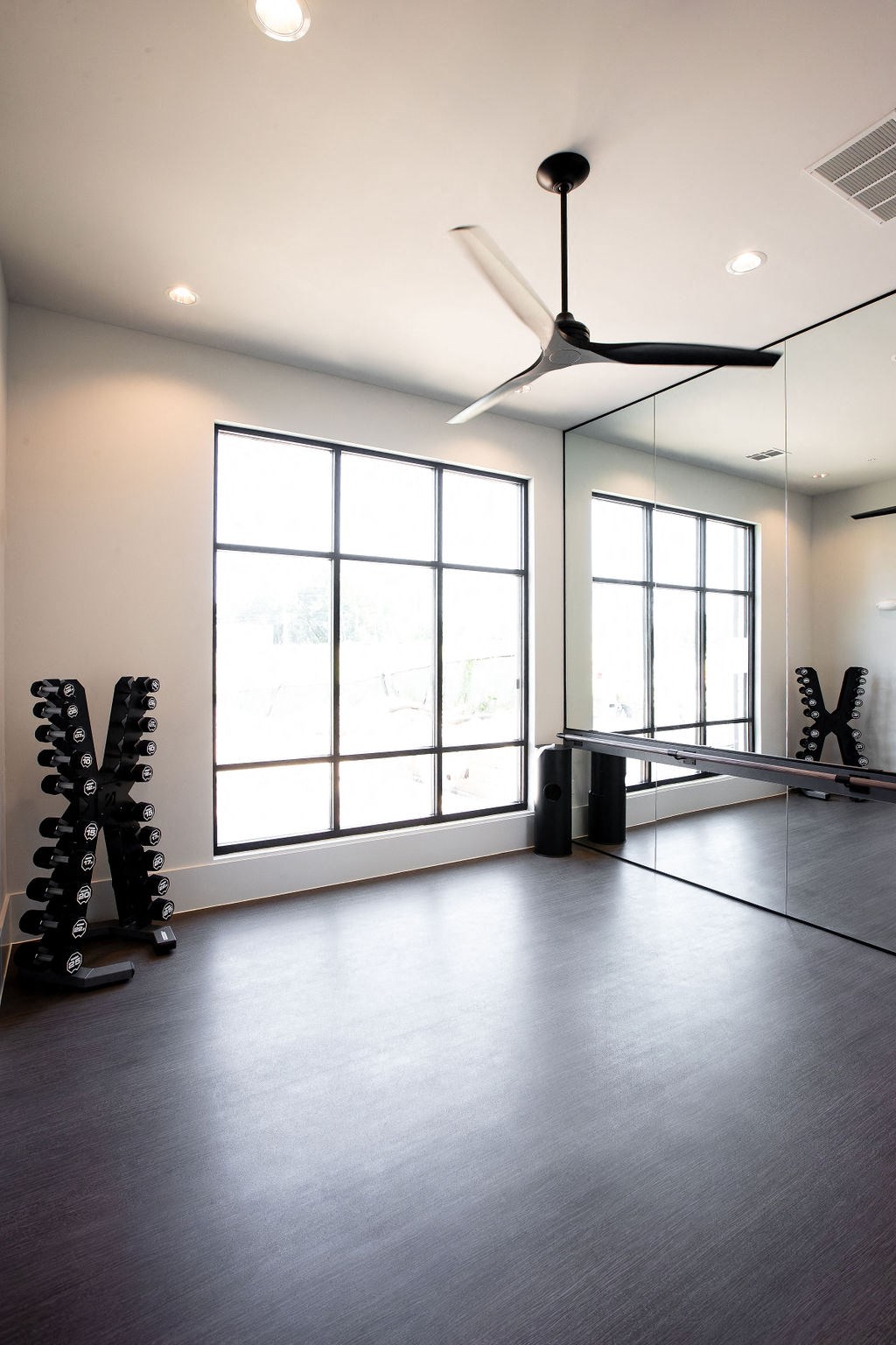 a workout room with a ceiling fan and dumbbells