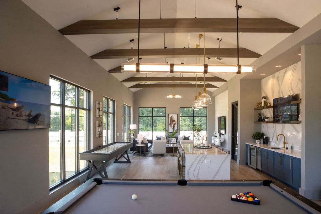 a pool table in the center of a living room with large windows