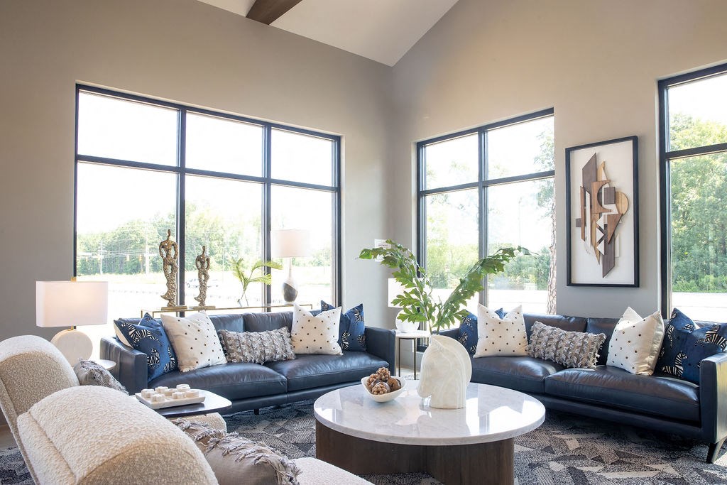 a living room with couches and a coffee table and large windows