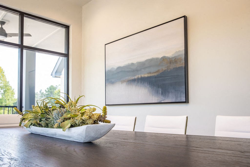 a dining room with a table and a painting on the wall