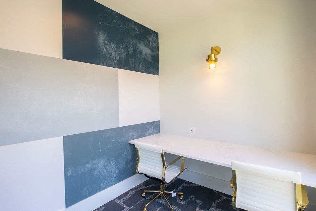 a desk and chair in a room with a wall and a lamp