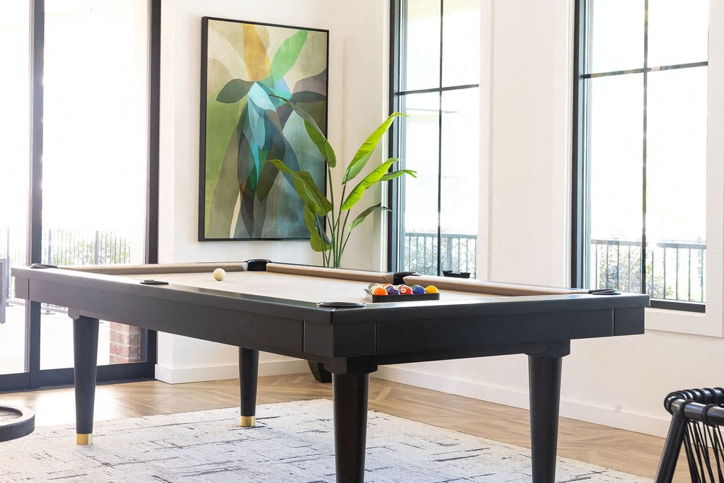 a pool table in a living room with windows