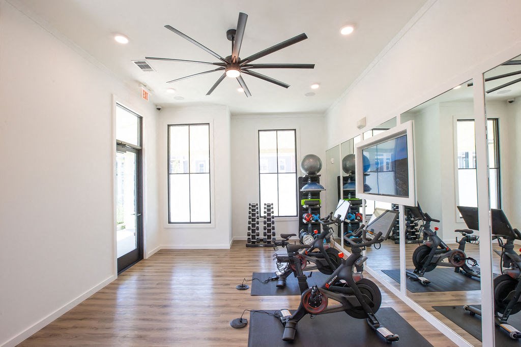the home gym has plenty of exercise equipment and a large tv