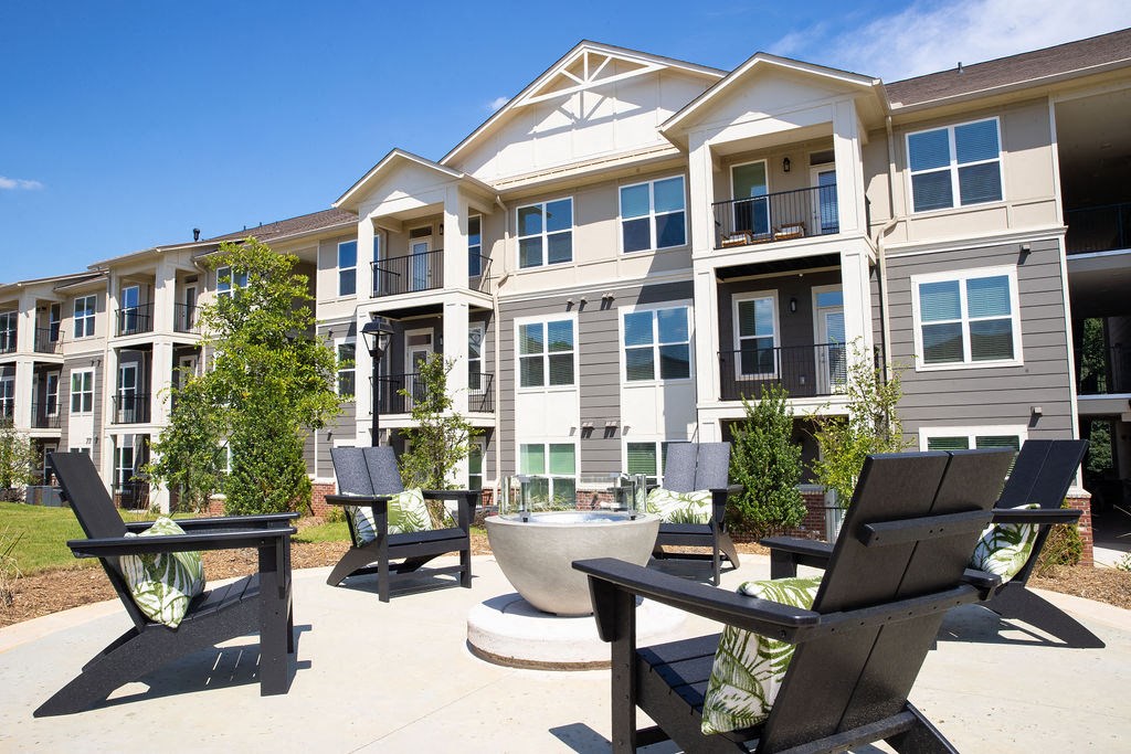 an outdoor area with chairs and tables in front of an apartment building