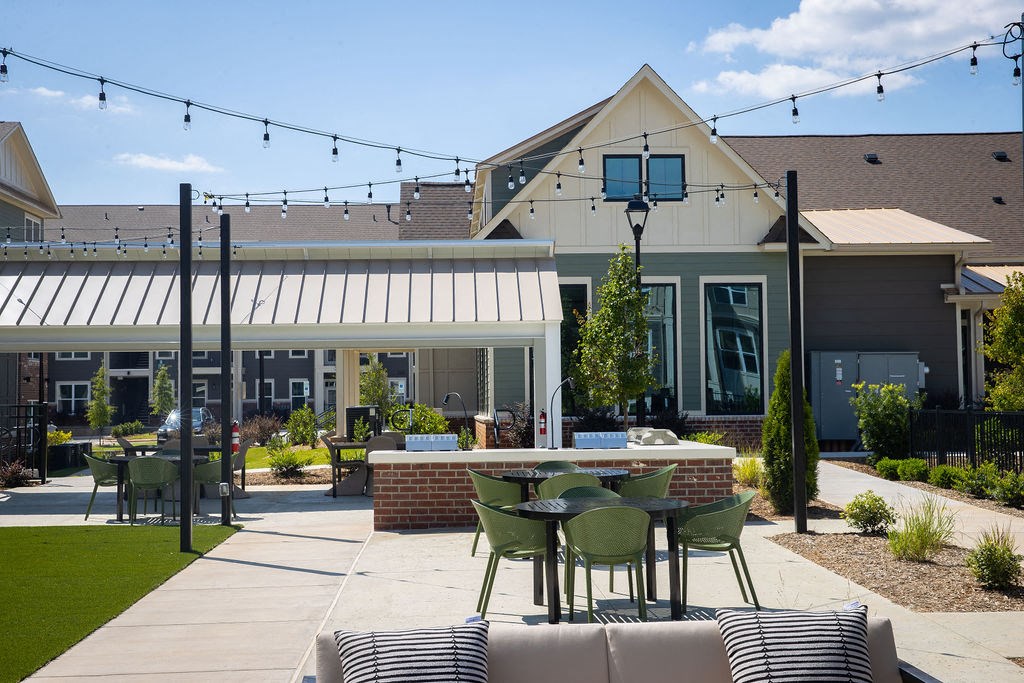 a patio with tables and chairs in front of a house