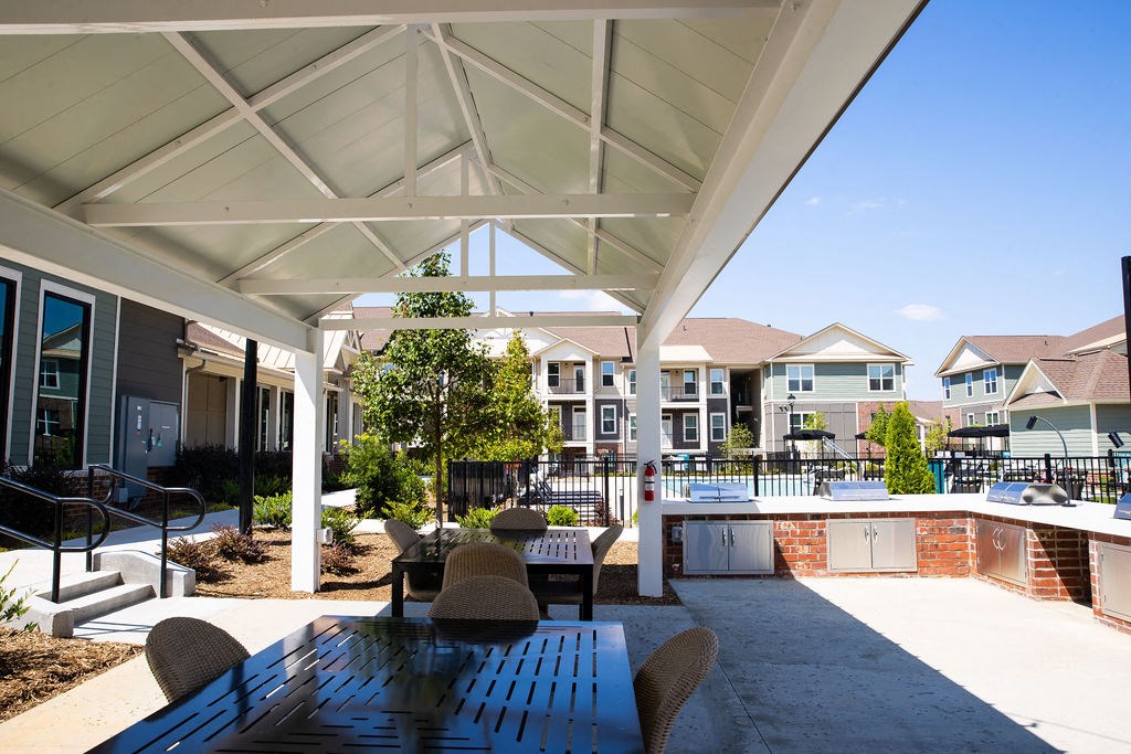 a covered patio with a table and chairs next to a pool