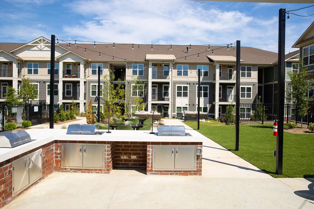an outdoor entertaining area with a patio and lawn in front of an apartment building