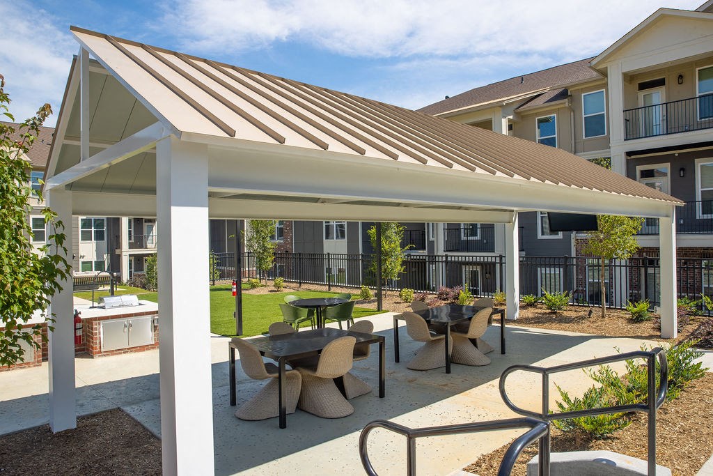 a patio with tables and chairs in front of an apartment building
