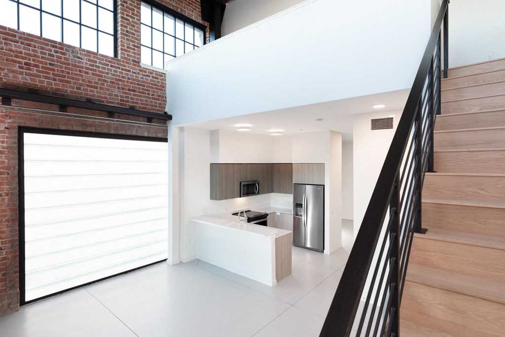 a white kitchen with a stainless steel refrigerator and a staircase