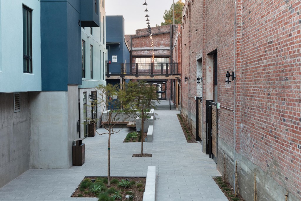 an alleyway between two brick buildings with trees in the middle
