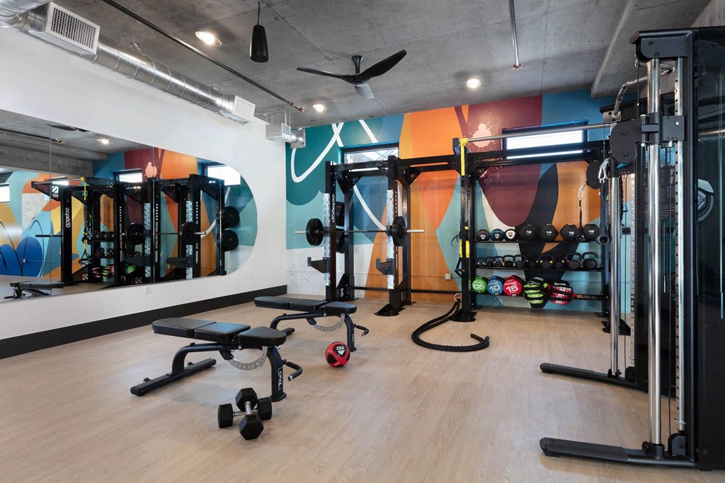 a gym with weights and other equipment in a room with a colorful wall