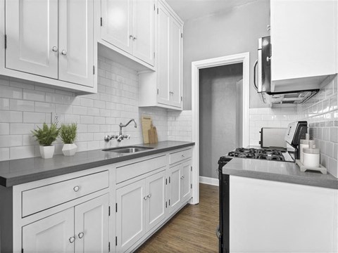 A kitchen with white cabinets and a black stove top.