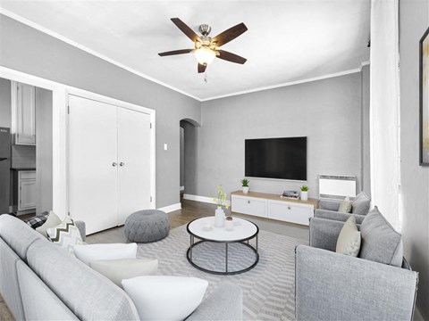 A living room with a grey couch, a white coffee table, and a ceiling fan.