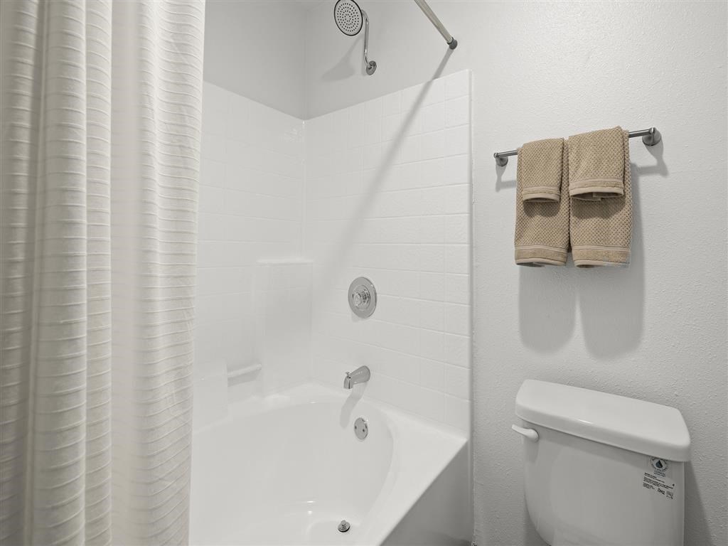 a white bathroom with a white toilet and a white bath tub at Enclave, Paramount, CA