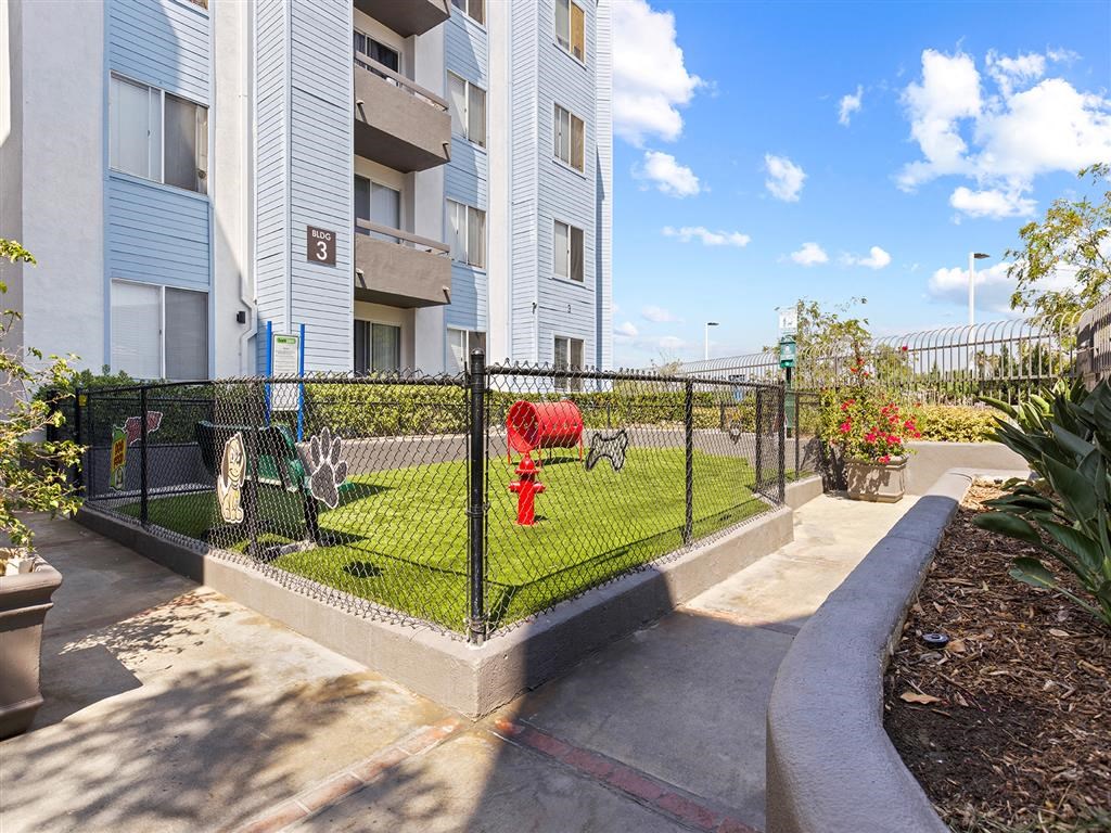 a fire hydrant in the middle of a grassy area in front of an apartment building at Enclave, Paramount California