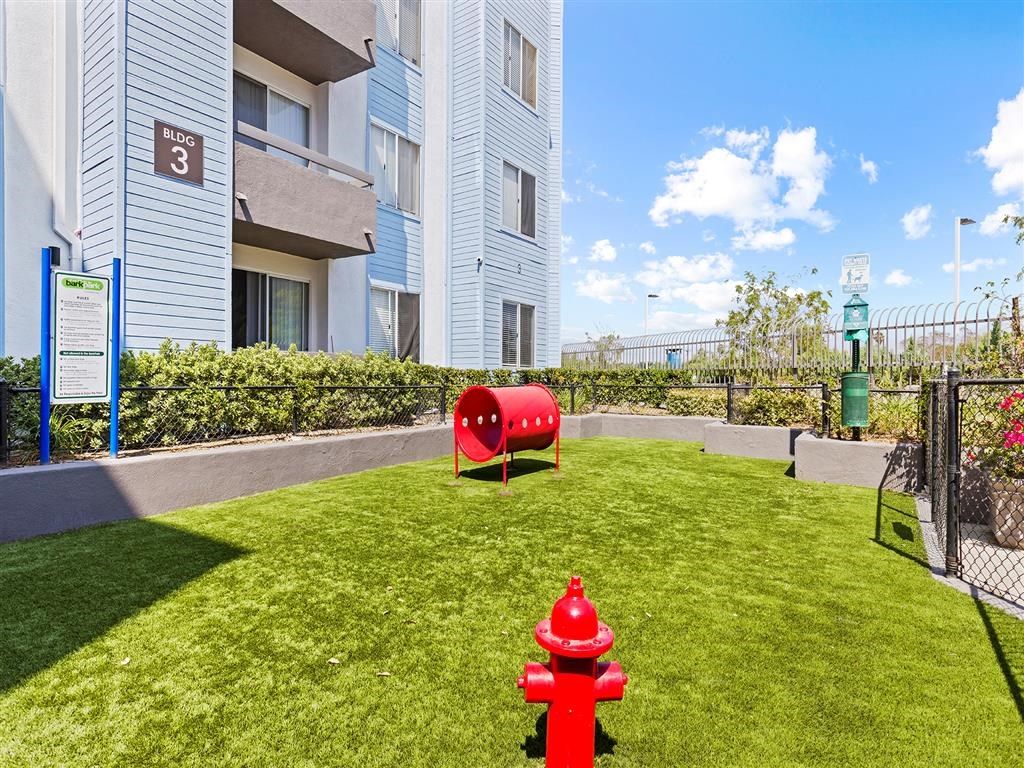 a red fire hydrant sitting on top of a lush green field at Enclave, Paramount