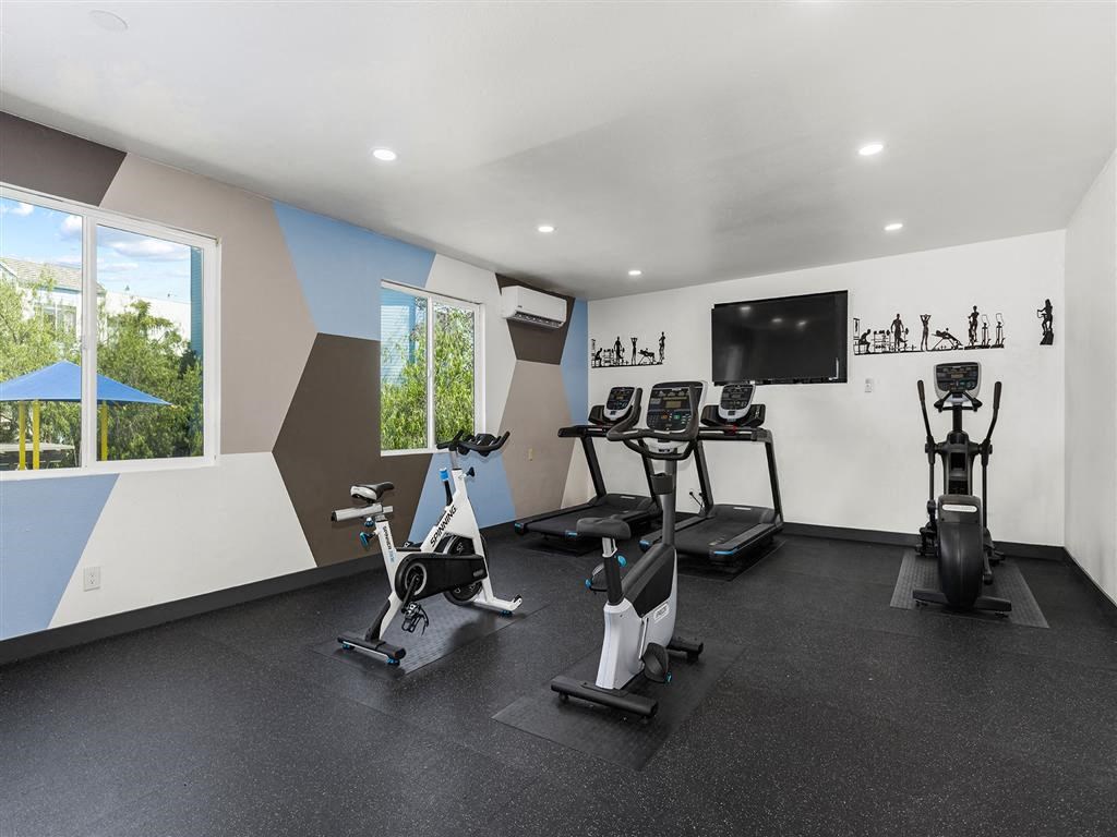 a room filled with lots of exercise equipment and a flat screen tv at Enclave, Paramount, CA