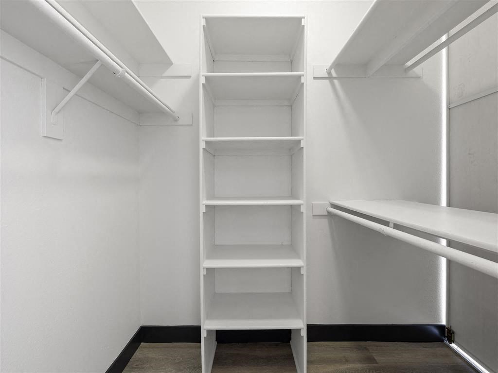 a walk in closet with a white shelving unit at Enclave, Paramount California