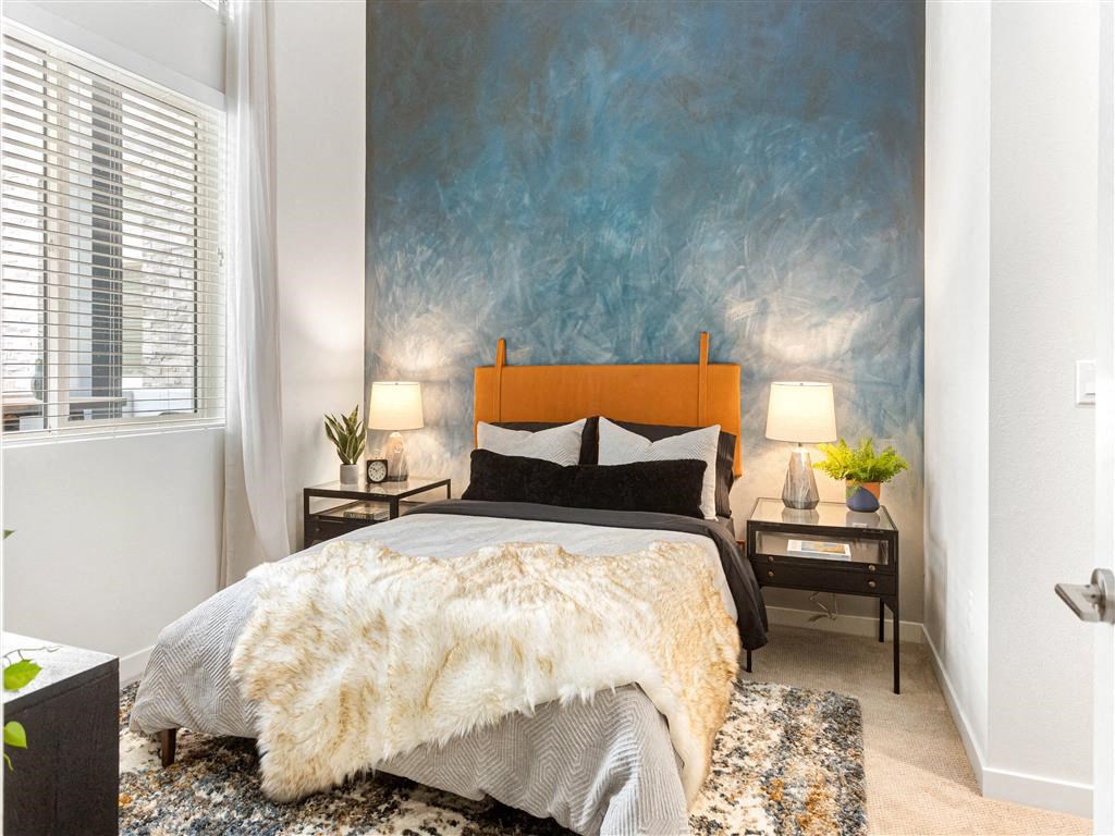 a bedroom with a bed and a blue painting on the wall