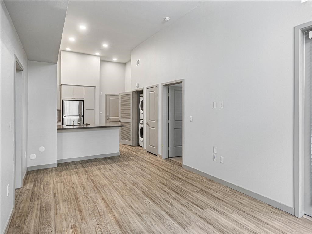 an empty living room and kitchen with a hard wood floor