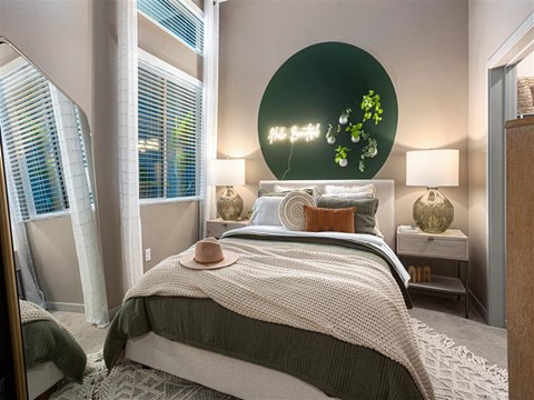 a bedroom with a bed and a green painting on the wall