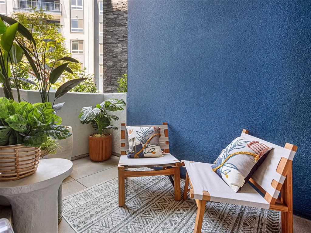 a small patio with two chairs and a blue wall