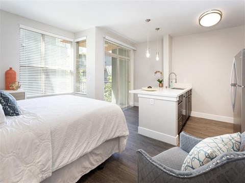 a bedroom with a bed and a kitchen with a sink