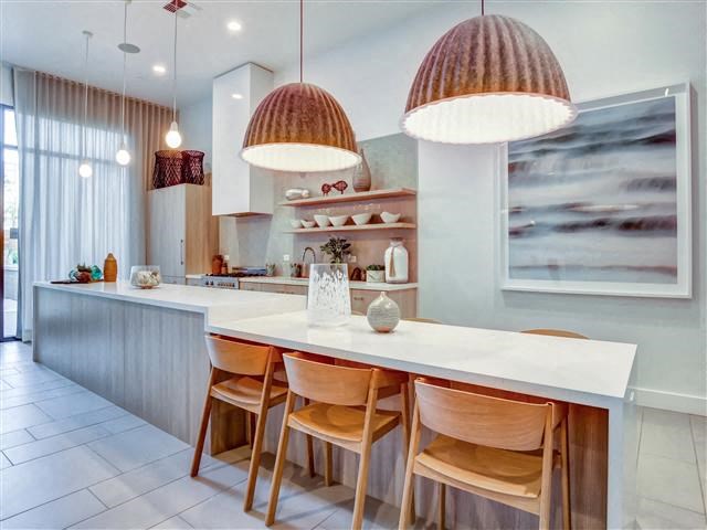 a kitchen with a white counter top and wooden chairs