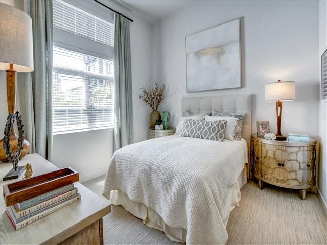 a white bedroom with a bed and a window