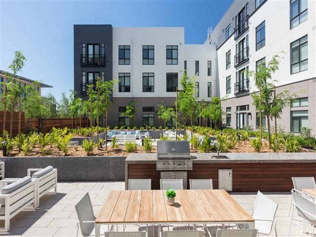 a patio with a table and chairs and a grill