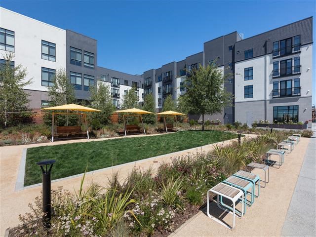 a courtyard with benches and umbrellas in front of some buildings