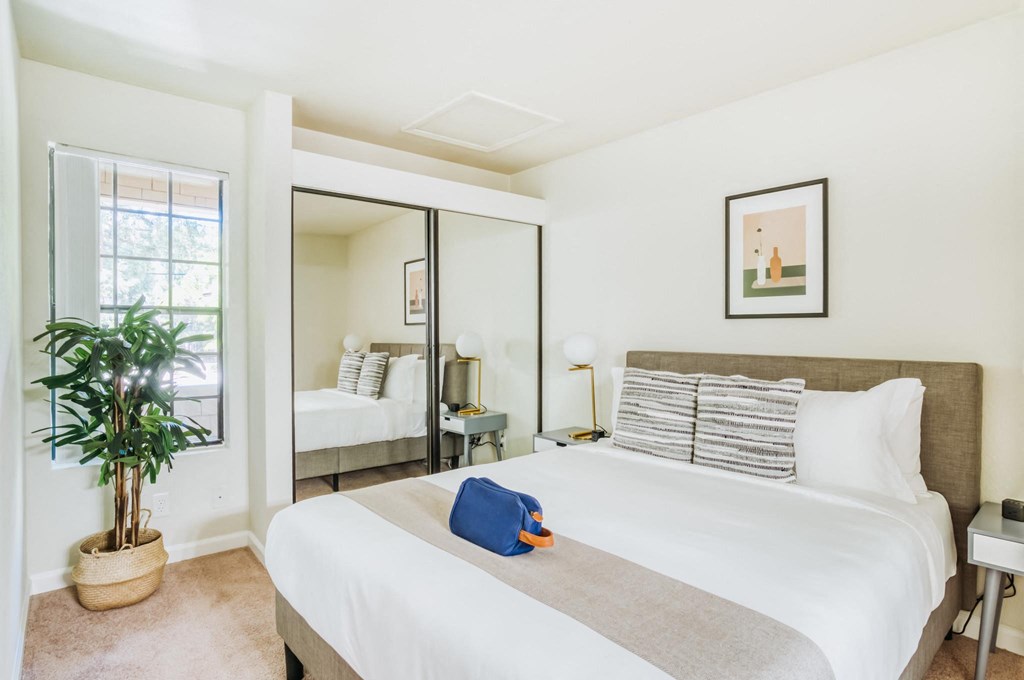 a bedroom with a large white bed and a mirror