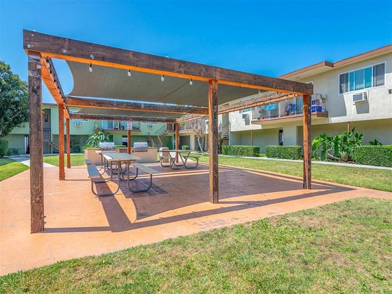 a patio with a table and chairs under a wooden structure at Citrus Court Apartments, Whittier, California