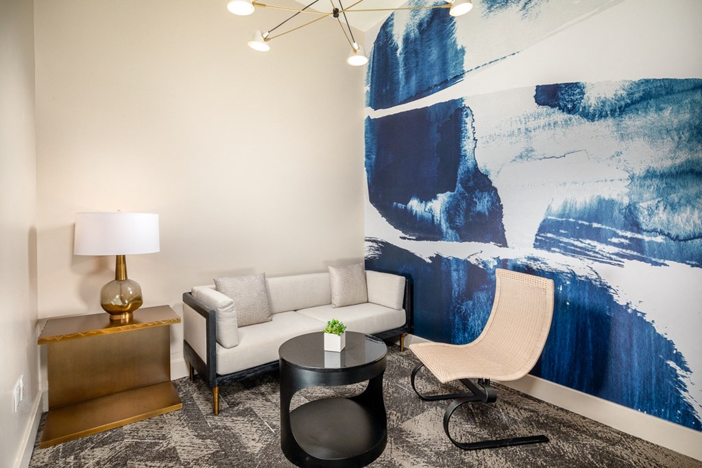 a living room with a couch and chair and a large painting on the wall