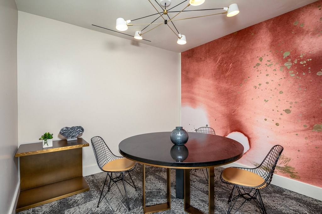 a dining room with a table and chairs and a wall with a red mural