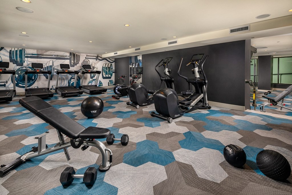a gym with cardio equipment and weights on the floor