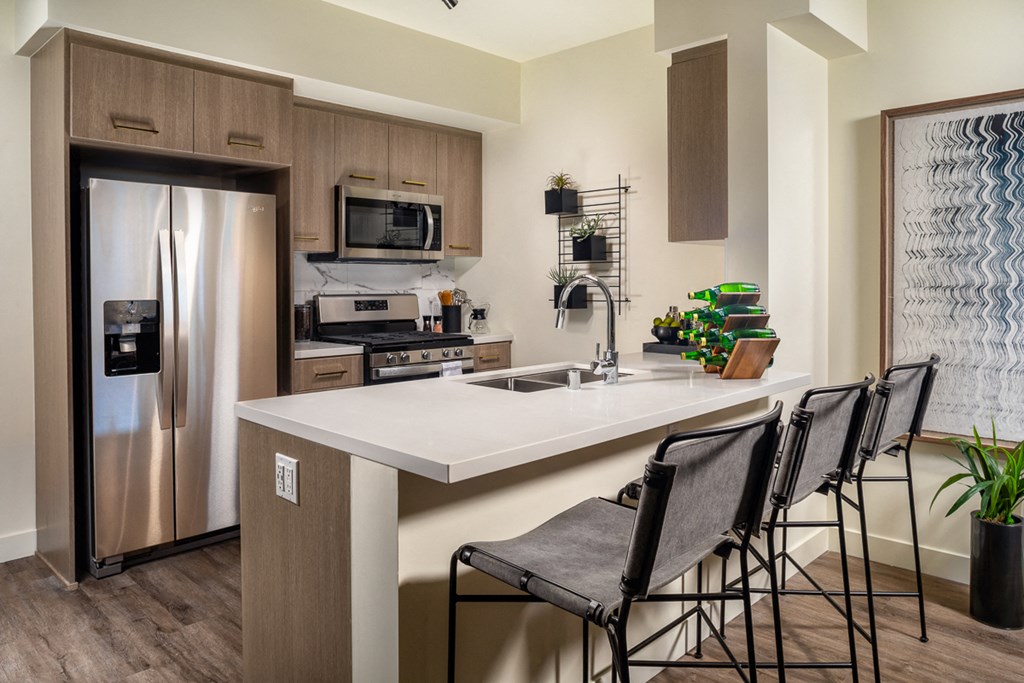 a kitchen with stainless steel appliances and a counter with three stools
